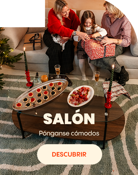 Escena de salón con una familia abriendo un regalo en el sofá, una mesa de centro con aperitivos y un ambiente acogedor